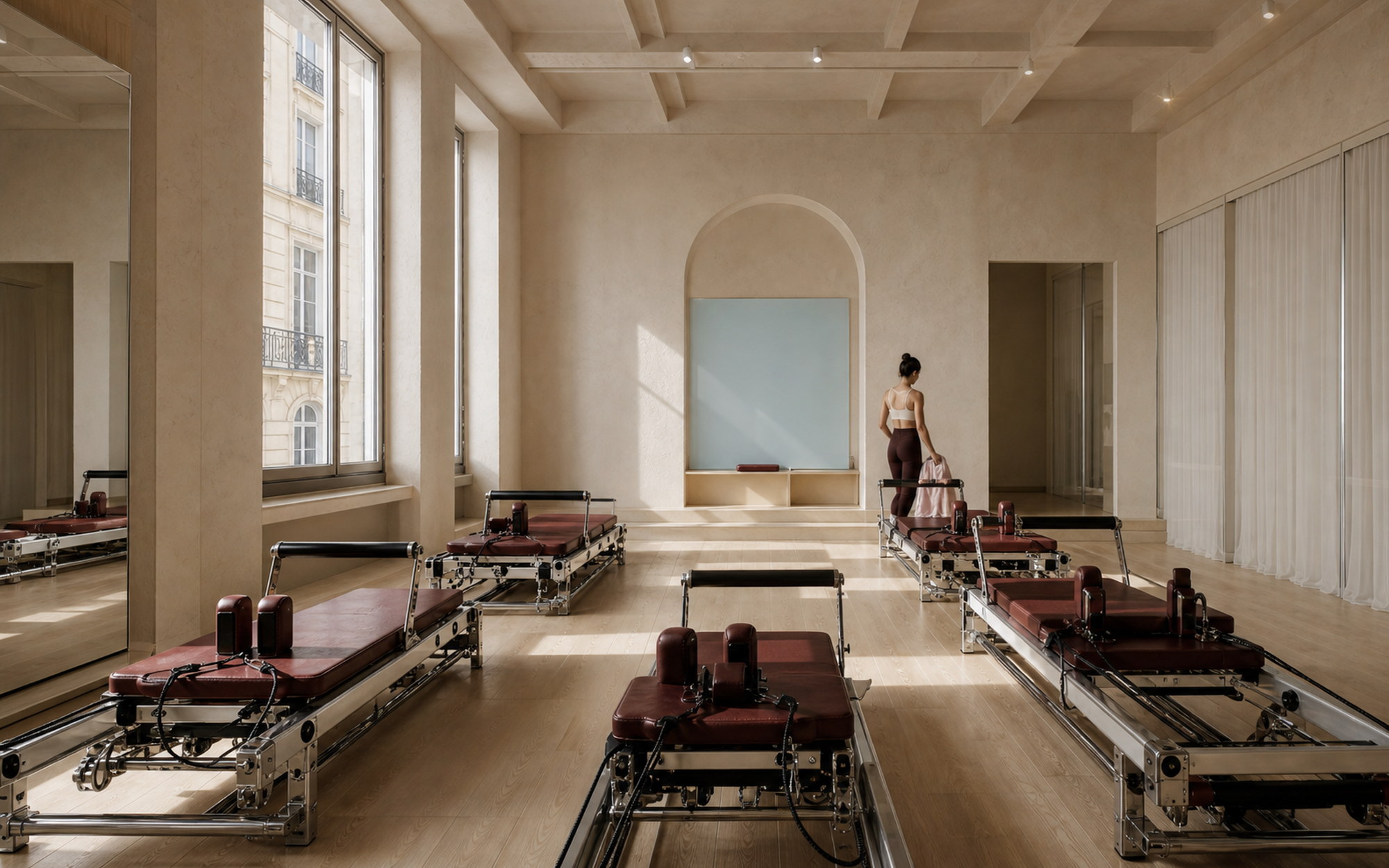 Salle de reformers KERA baignée de lumière, avec appareils bordeaux et sol en chêne clair